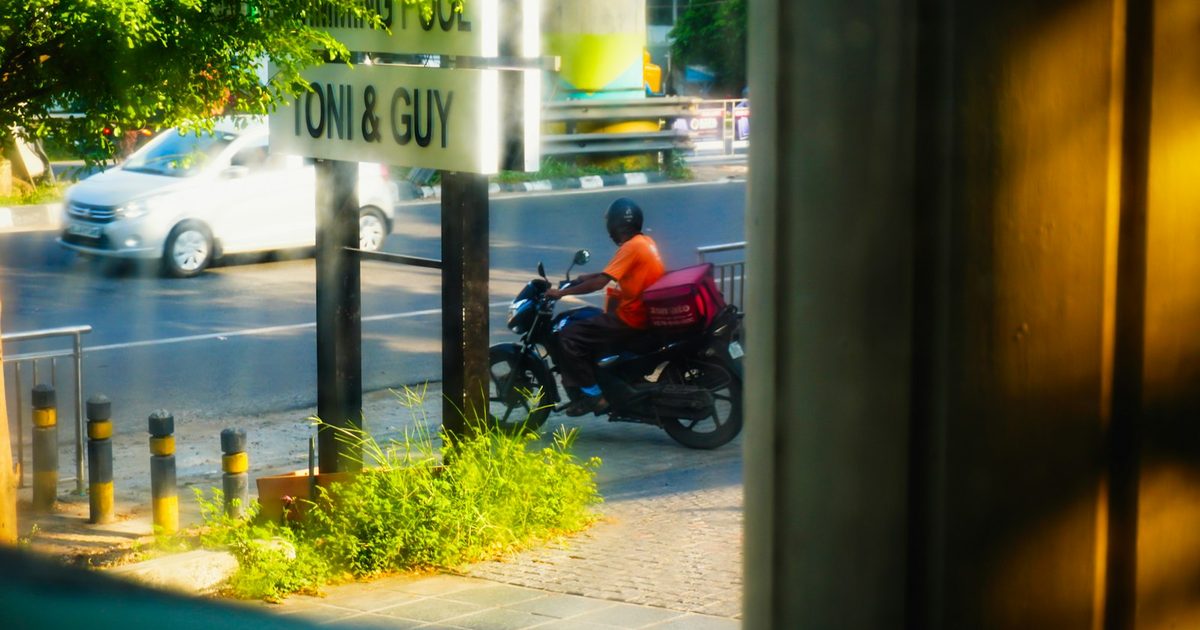 Motorista de aplicativo com baú de entrega em via urbana, tema do julgamento do STF sobre vínculo de emprego na uberização (Tema 1.291)